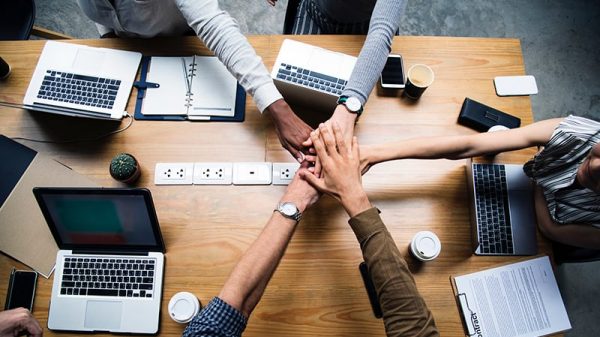 tech-online Technology team work with hands in middle of desk with laptops